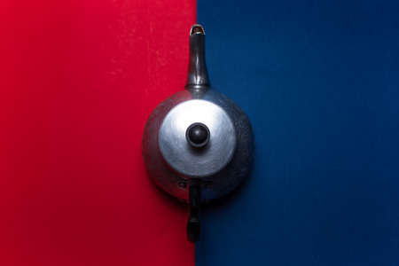 Top view of vintage aluminum teapot on two backgrounds of red and blue colors.