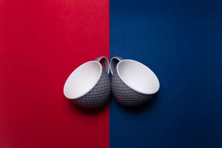 Top view of two ceramic grey mugs on two backgrounds of red and blue colors.