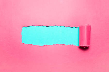 Diagonally torn pink paper with space for text of cyan background.の写真素材