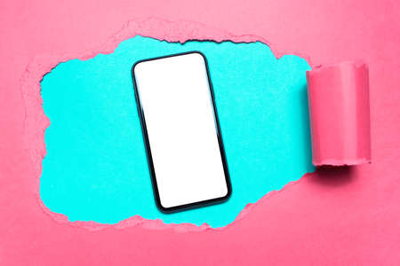 Diagonally torn yellow paper, smartphone with mockup in hole on background of cyan or aqua menthe color.の写真素材