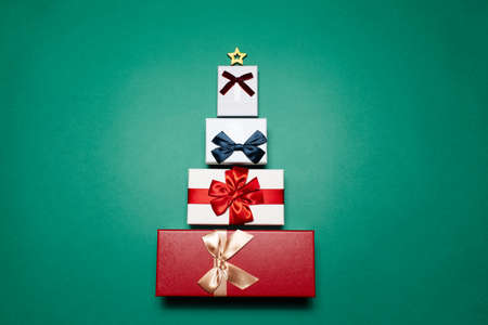 Top view of gift boxes laid out in the shape of Christmas tree, on background of green color.の写真素材