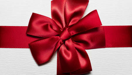 Close-up of red wrapping ribbon in shape of bow for white gift box.