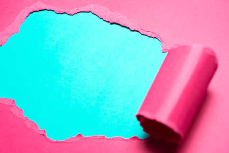 Close-up of torn pink paper with space for text of cyan background.の写真素材