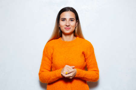 Studio portrait of businesswoman in orange sweater on white background.の写真素材
