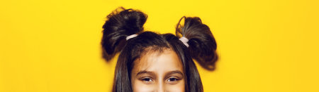 Funny hair buns of teenage girl on background of yellow color.の写真素材
