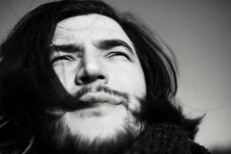 Black and white close-up portrait of young guy with long hair.