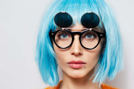 Close-up portrait of young pretty girl with blue hair and round shades.の写真素材