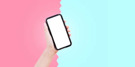 Close-up of hand holding smartphone with mockup on two backgrounds of pink and cyan colors.の写真素材