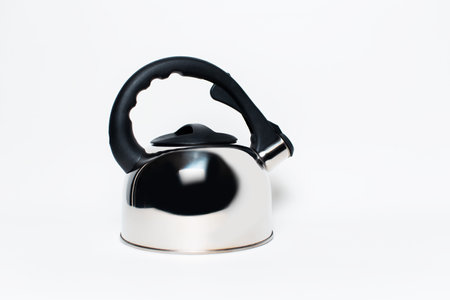 Studio portrait of metallic shiny teapot, with black handle, on the background of white wallの写真素材