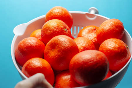 Close-up picture of a big bowl with juicy mandarins, on the background of light blue wall.の写真素材