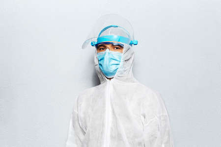 Portrait of a doctor wearing PPE suit, on the background of white wall. Pandemic concept.の写真素材
