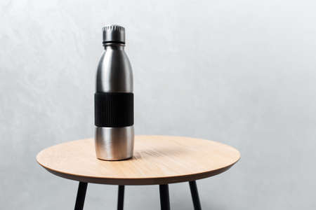 Close-up of steel reusable thermo water bottle on wooden table.の写真素材