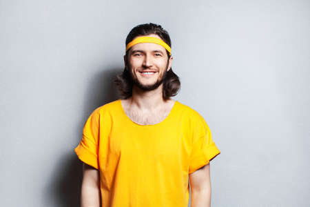 Portrait of young smiling guy in yellow shirt on background of grey wall.の写真素材