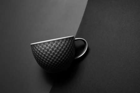 Black and white photo; closeup of tea cup on textured wall.の写真素材