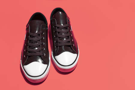 Close-up of pair of vintage sneakers shoes on coral pink background.の写真素材