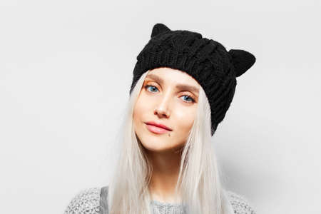 Studio portrait of young blonde pretty girl wearing black hat with cat ears on white background.の写真素材