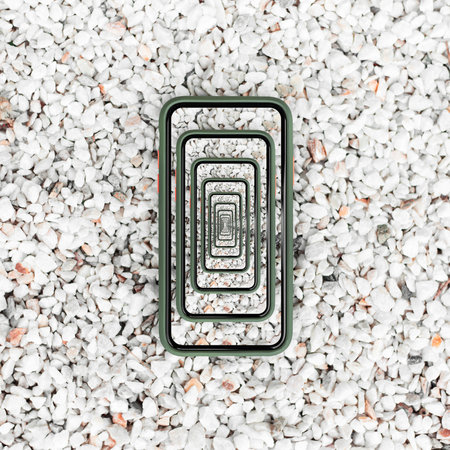 Enigmatic surrealistic optical illusion. Close-up of smartphone on white small stones.