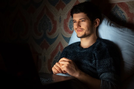 Young man lying home and looking in laptop.