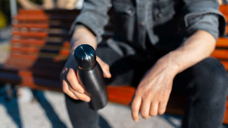 Close-up of male hands, holding steel reusable thermo water bottle of black. Eco bottles, zero waste, no plastic.の写真素材