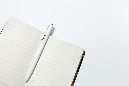 Close-up of empty notebook and pen, isolated on white background.