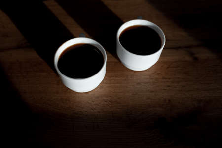 Top view of two white cups of coffee on wooden table.の写真素材