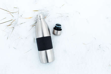 Top view of steel reusable flask near bottle cap on snow.の写真素材
