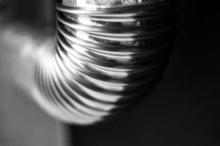 Black and white photo; close-up of stainless pipe with round corner on black-grey background.の写真素材