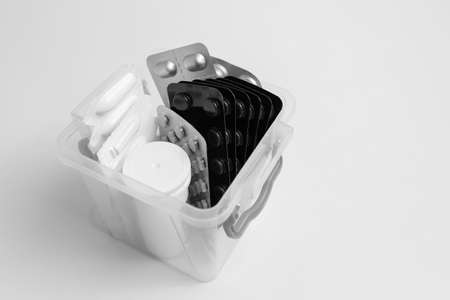Close-up of small first aid kit with different pills against white background.