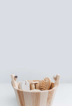 Close-up of some bath accessories in small wooden bucket against white studio background with copy...