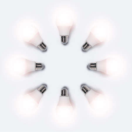 Many glowing light bulbs in shape of circle isolated on white background. Business idea concept.