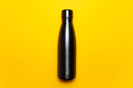 Close-up of black reusable steel thermo bottle for water on background of yellow color.の写真素材