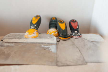 Close-up of many used putty knifes on wooden table.の写真素材