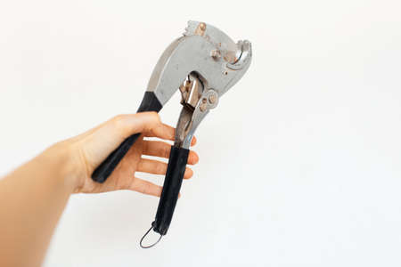 Female hand holding plumbing scissors on white background.