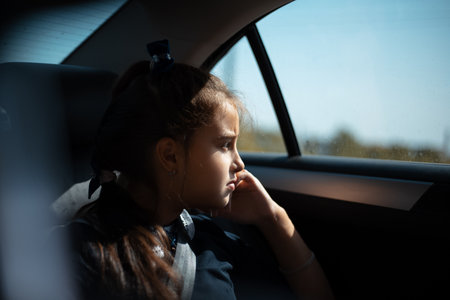 Portrait of child girl sitting in the car, looking at the window.の写真素材