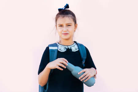 Teenage girl holding reusable bottle on pink background.の写真素材