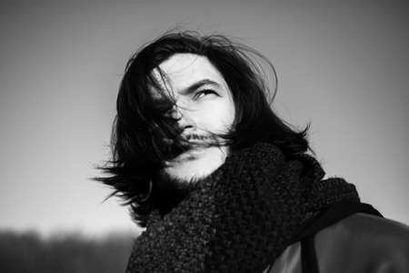 Portrait of young handsome man with long dark hair.