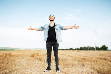 Outdoor portrait of young man with denim jacket, standing on the haystack.の写真素材