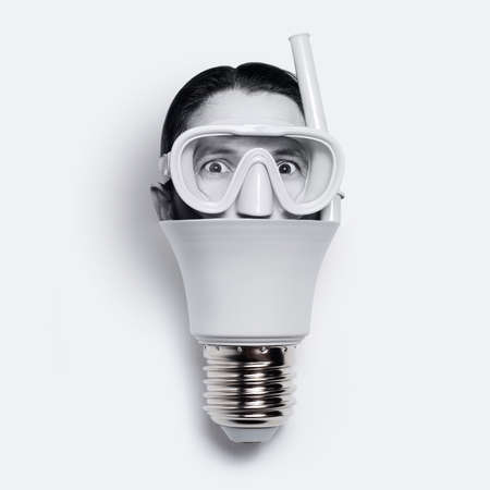 Close-up of light bulb with male head wearing diving mask, isolated on white.の写真素材
