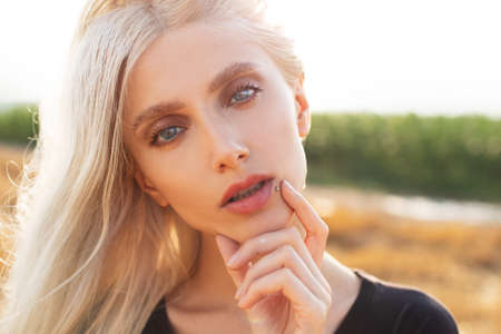 Close-up portrait of young pretty blonde girl in the wheat field.