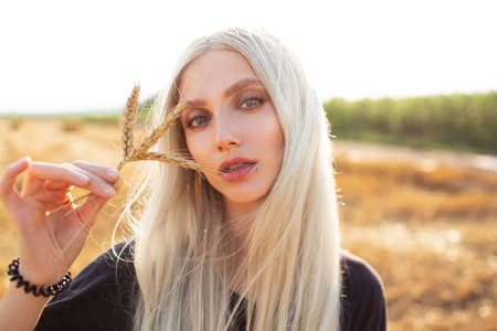 Outdoor portrait of young beauty  blonde girl holding some wheat spikes.の写真素材