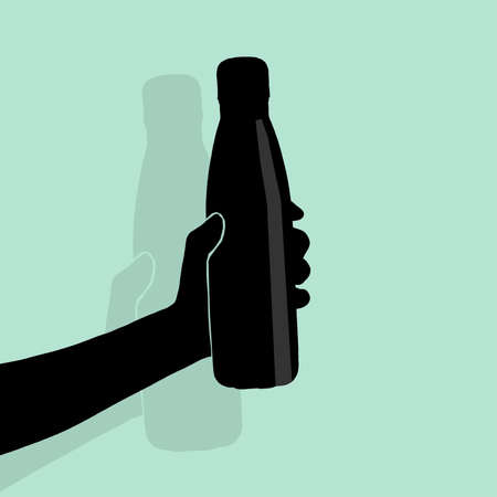 Close-up of hand holding bottle on green background.の写真素材