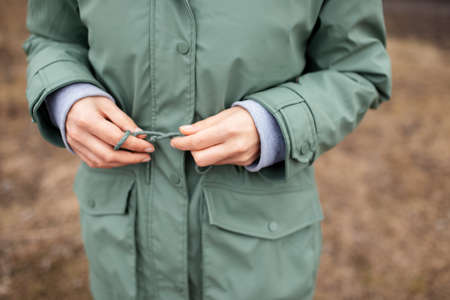 Close-up photo of woman in green trench, walking in the park.の写真素材