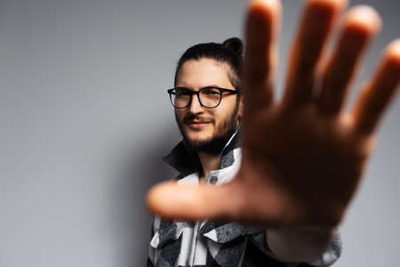 Studio portrait of young smiling  handsome man, gesturing 'stop' sign.の写真素材
