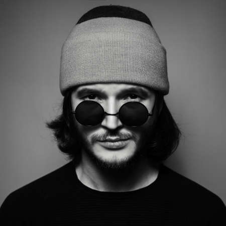 Black and white, close-up portrait of young man wearing sunglasses and hat.の写真素材