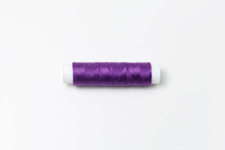 Close-up of purple thread spool isolated on white background. Very peri color.