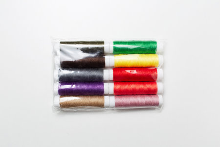 Close-up of sealed colorful thread spools isolated on white background.
