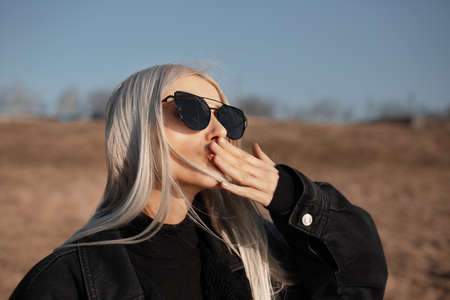 Outdoor portrait of cheerful blonde girl, sends kisses, wearing sunglasses.の写真素材