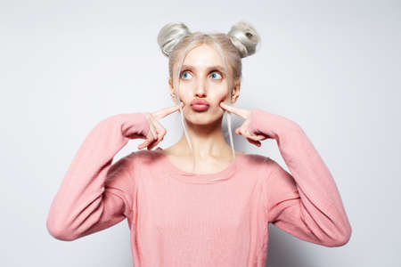 Studio portrait of beautiful blonde girl with buns, have fun, sending kisses.の写真素材