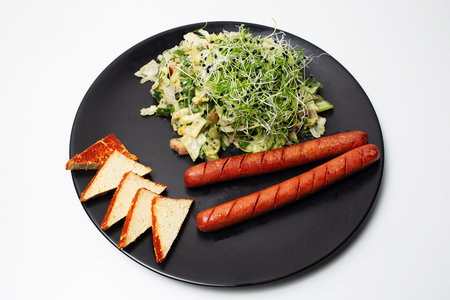 Vegan food. Salad, tofu and plant based sausages in black plate on white.の写真素材