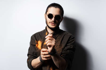 Portrait of young man adjusting the strap of his watch on white background.